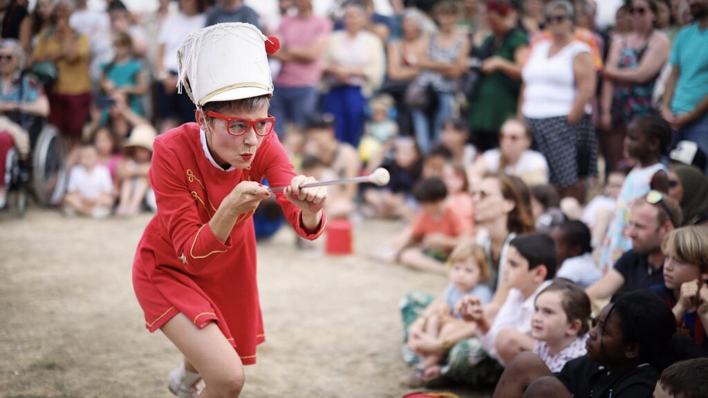 Gros plan sur une des Mijorettes, en arrière plan enfants et adultes assistant au spectacle