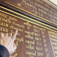 Une main montrant un nom sur une plaque mémorielle