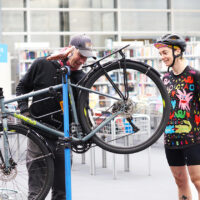 Deux personnes dans la médiathèque en train de réparer un vélo au milieu des livres