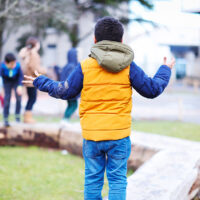Un enfant dans la cour de l'école Ragon, en train de marcher sur les bancs en bois.